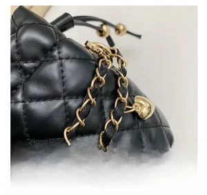 Close-up of black quilted leather bucket bag with gold chain strap and heart charm