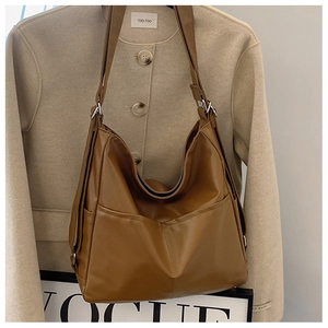 Detail of caramel leather tote showing side pocket and adjustable strap on a blazer