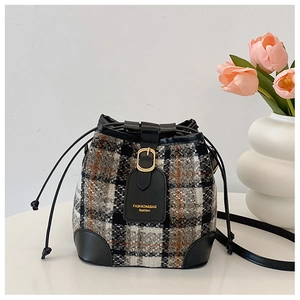 Detail of checkered tweed bucket bag showing the drawstring closure and leather logo patch