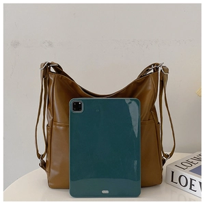 Detail view of large brown leather tote bag holding a tablet for size reference