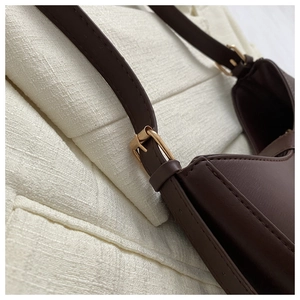 Gros plan sur la boucle de la sangle et les coutures du sac à bandoulière en cuir marron
