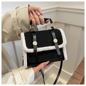 Close-up of black crossbody bag featuring white faux shearling trim and golden buckles