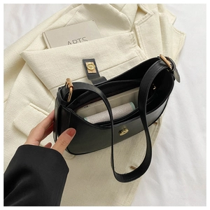 Vue intérieure du sac croissant noir vintage montrant le compartiment sur un blazer beige