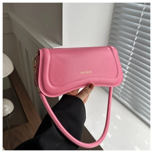 Close-up of pink leather shoulder bag with gold XM & BAGS logo and sleek curved design