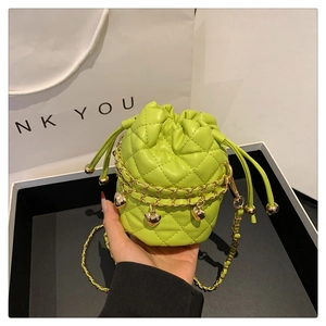 Close-up of quilted green bucket bag with gold chain and heart charm detail