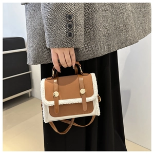 Detail of plush fleece and brown leather stitching bag with a gold metal clasp buckle