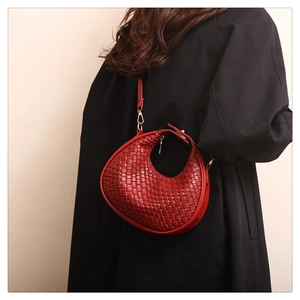 Detail of dark red woven crescent bag with textured leather and gold metal hardware