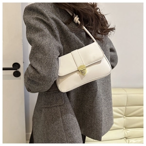 Detailansicht der weißen Baguette-Tasche mit Goldschnalle auf grauem Blazer-Sakko