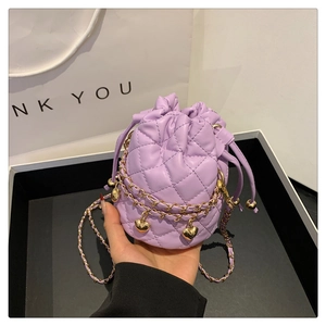 Detail of light purple quilted bucket bag with gold chain and heart charm