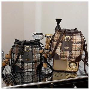 Detail of plaid bucket bags with leather trim and rabbit charms on a vintage shelf