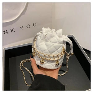 Macro shot of white quilted mini bucket bag with gold chain and heart charms detail