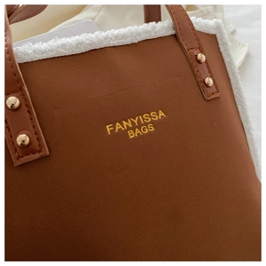 Close-up of brown suede tote bag featuring plush white faux fur trim and gold logo