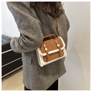 Detail of plush lamb wool and brown leather patchwork crossbody bag with gold buckles