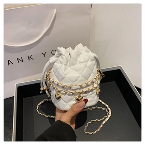 Close-up of quilted white bucket bag with gold heart charms and chain strap