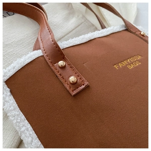 Detail of brown tote bag with white faux fur trim and gold rivet reinforcement