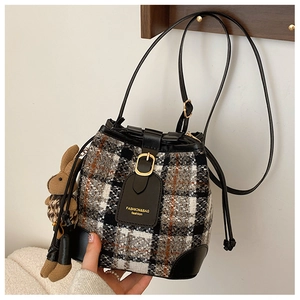 Detail of checkered tweed bucket bag with drawstring closure and cute rabbit charm