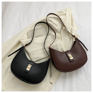 Gros plan sur les sacs croissants noir et café avec boucle dorée sur un blazer blanc
