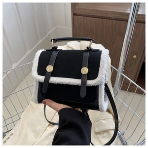 Close-up of black leather crossbody bag featuring white faux shearling trim and gold hardware