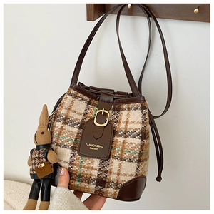 Detail of plaid wool bucket bag with leather strap and cute rabbit pendant