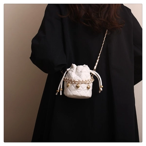 Close-up of white quilted bucket bag with gold chain and heart charm details