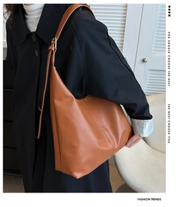 Detail of a large brown hobo shoulder bag featuring a smooth glossy finish and metal buckles