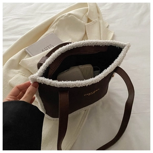 Detail view of large brown suede tote bag with plush white faux fur trim and gold logo