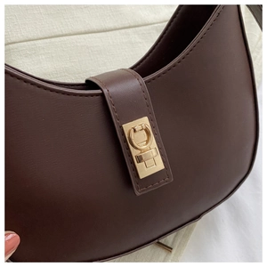 Détail du sac selle croissant marron foncé avec cuir texturé et boucle dorée circulaire