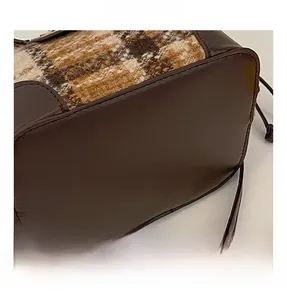 Detail view of vintage plaid wool and brown leather bucket bag with premium stitching