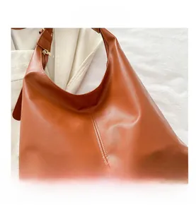 Detailed close-up of brown PU leather hobo bag with gold metal zipper and stitching
