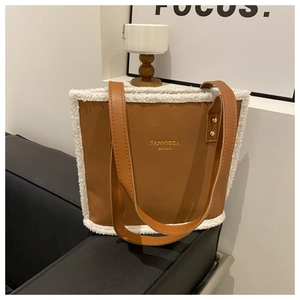 Close-up of brown suede tote bag featuring white faux shearling trim and gold brand logo
