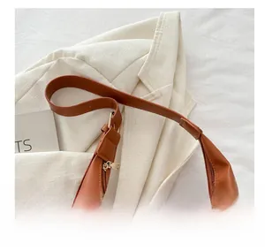 Close-up of brown PU leather tote bag with adjustable shoulder strap and gold buckle detail