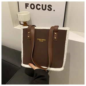 Brown leather tote bag with white faux fur trim and gold rivets shown in a modern setting