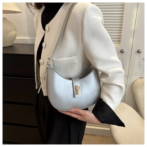 Détail d'un sac à bandoulière argenté en demi-lune avec fermoir à anneau doré