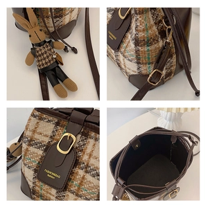 Detail view of plaid bucket bag with tweed fabric, brown leather trim, and cute bunny charm
