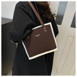 Detail of brown tote bag featuring plush white faux shearling trim and brand logo