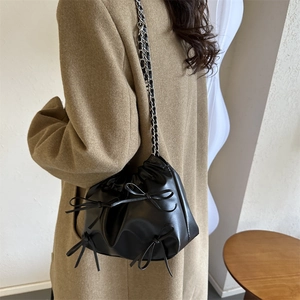 Schwarze Bucket-Bag mit Falten-Design, Schleifen und Kettenriemen am Model gezeigt