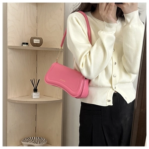Detailed view of a pink glossy shoulder bag with gold logo and metallic chain strap