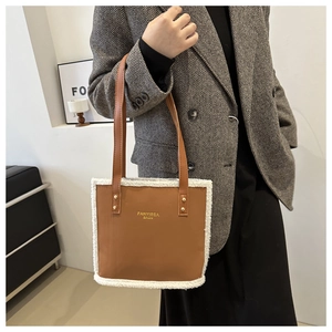 Brown leather tote bag featuring plush white faux shearling trim and gold rivet details