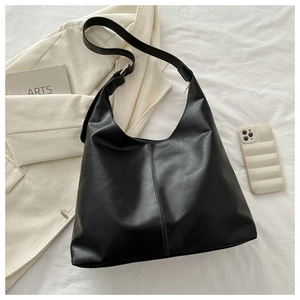 Close-up of a black matte leather tote bag with center seam detail and adjustable strap