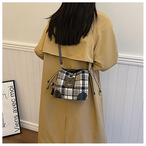 Close-up of model wearing wool plaid bucket bag with adjustable leather shoulder strap