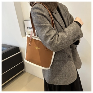 Detail of a brown faux suede tote with white faux fur trim and gold logo on long straps