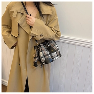 Detail of wool plaid bucket bag featuring leather trim and a cute plush rabbit charm
