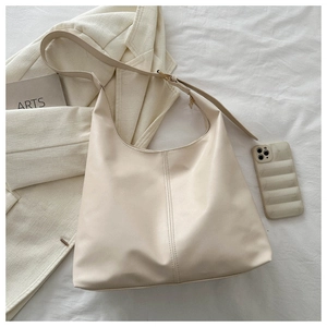 Detail of minimalist cream hobo bag with adjustable strap and golden hardware accents