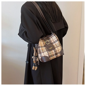 Detail view of vintage plaid bucket bag with brown leather trim and plush rabbit charm