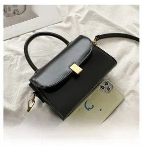 Detailed comparison of the small black vintage crossbody bag next to a smartphone