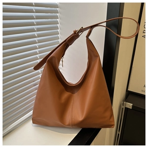 Detail view of caramel brown PU leather hobo bag with top zipper and gold metal buckle