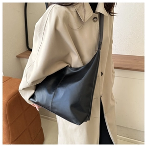 Side view of black PU leather hobo tote bag featuring vertical stitching and shoulder strap