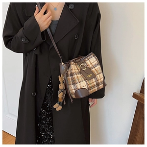 Detailed view of plaid tweed bucket bag with leather trim and cute rabbit charm