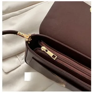 Detail of smooth metal zipper and internal zip pocket of dark brown leather shoulder bag