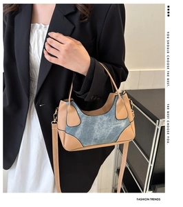 Detail of color-block baguette bag in tan leather and denim on model with black blazer